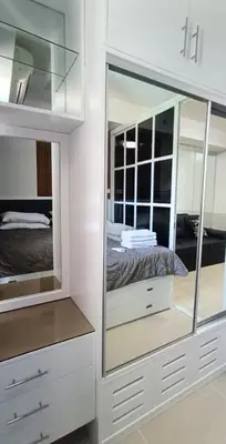 a white bedroom with a bed and a mirror at One-bedroom condo at Shell Residences in Manila