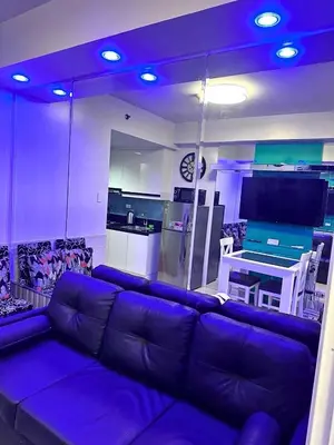a living room with a purple couch and a kitchen at One-bedroom condo at Shell Residences in Manila