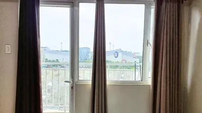 a window with curtains and a view of a building at Spacious simple one-bedroom condo at Shell Residence in Manila