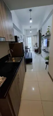 a kitchen with a sink and a living room at Cozy 1 Bedroom unit in Manila in Manila
