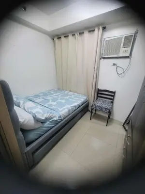 a small bedroom with a bed and a chair at Apartment Condo Unit 1-br Self-contained in Manila