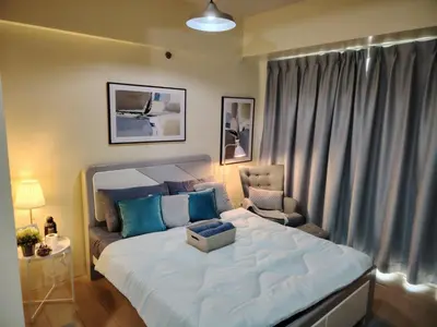 a bedroom with a large bed and a chair at Cheap Accommodation - Newport Boulevard in Manila