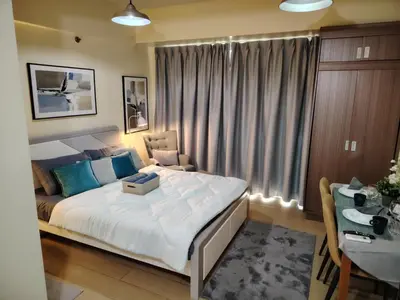 a bedroom with a large bed with a desk and a table at Cheap Accommodation - Newport Boulevard in Manila