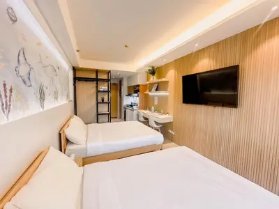 a small room with two beds and a flat screen tv at Hotel-Like Staycation 4 near MOA with WiFi & Netflix in Manila