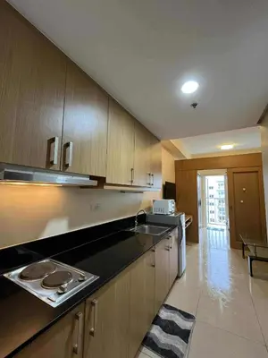 a kitchen with wooden cabinets and a counter top at Dona staycation in Manila