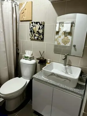 a bathroom with a white toilet and a sink at Miyu's Staycation Place in Biñan