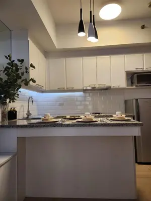 a kitchen with white cabinets and a granite counter top at Modern Bright Cozy Stylish 1BR Venice BGC Balcony in Manila