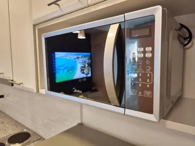 a microwave oven hanging on a kitchen counter at Modern Bright Cozy Stylish 1BR Venice BGC Balcony in Manila