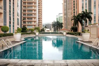 a large swimming pool in a city with tall buildings at Cozy & Spacious 2BR Stay Near BGC - Home Theater in Manila
