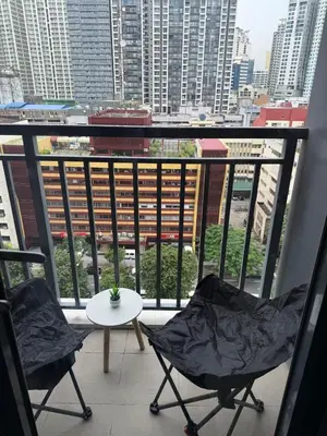 two chairs and a table on a balcony with buildings at Red Residences Cozy Condo in Makati Near NAIA in Manila