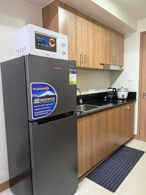 a kitchen with a refrigerator with a microwave on top at Red Residences Cozy Condo in Makati Near NAIA in Manila