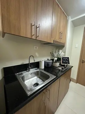 a kitchen with a sink and wooden cabinets at JM's CRIB in Manila