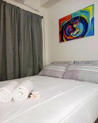 a bedroom with a bed with towels and a painting at Brand New 2 Bedder near Malls SMDC Bloom in Manila
