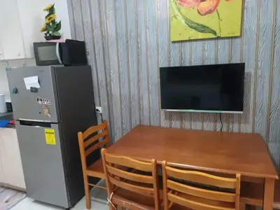 a kitchen with a table and a refrigerator and a television at Sea residence MOA KC PLACE in Manila