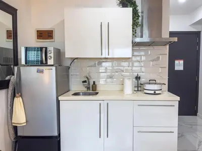 a kitchen with white cabinets and a white refrigerator at Unique and Quiet Studio Unit in Mandaluyong or Makati with Fast WiFi & Best City View in Manila
