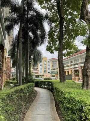a walkway through a park with palm trees and buildings at DBK HOMES Sorrento Oasis in Manila