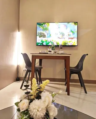 a living room with a table with chairs and a flat screen tv at Condo in BGC - Uptown Mall in Manila