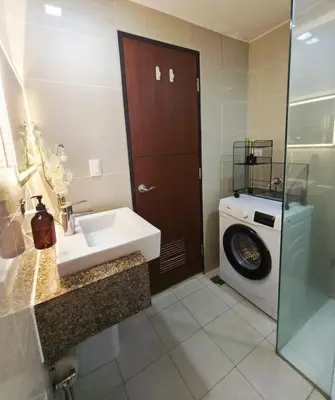 a bathroom with a sink and a washing machine at Condo in BGC - Uptown Mall in Manila