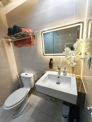a bathroom with a sink and a toilet and a mirror at Condo in BGC - Uptown Mall in Manila