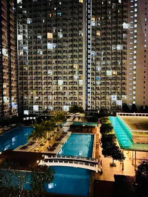 a view of a large building with a pool at night at Your Urban Oasis in the Heart of Makati in Manila