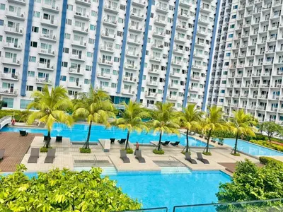 a pool with palm trees in front of a large building at Your Urban Oasis in the Heart of Makati in Manila