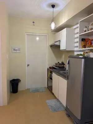 a small kitchen with a refrigerator and a door at Stylish 1bedroom apartment at Muntinlupa in Manila
