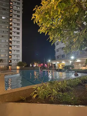 a swimming pool at night with two tall buildings at Stylish 1bedroom apartment at Muntinlupa in Manila