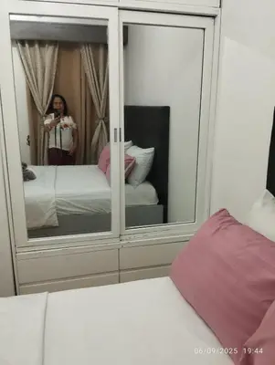 a woman taking a picture of a mirror in a bedroom at HAPpycation Portocondo in Manila