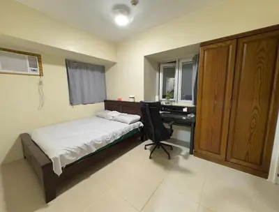 a bedroom with a bed and a desk with a computer at Leos room in Manila