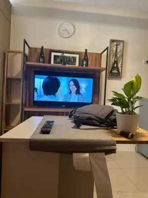 a living room with a television and a table with a remote control at Koro Den at Shore Residences in Manila
