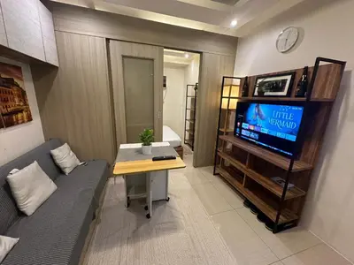 a small living room with a couch and a tv at Koro Den at Shore Residences in Manila