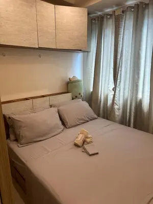 a bed with a book and a stuffed animal on it at Koro Den at Shore Residences in Manila