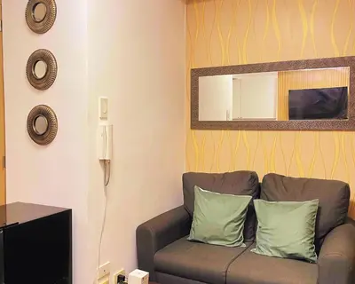a living room with a couch and a mirror at Charm's City Escape at Grace Residences in Manila