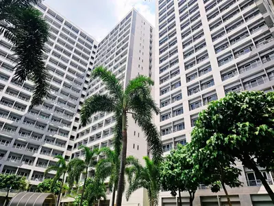 a group of tall buildings with palm trees in front at Charm's City Escape at Grace Residences in Manila
