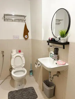 a bathroom with a toilet and a sink and a mirror at Roomies Spacious Fully Furnished Condo with Balcony and Netflix for 4pax in Manila