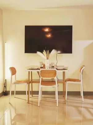 a dining room table with chairs and a tv on the wall at Condo- Park McKinleyWest Big1Br unit -Pool View in Manila