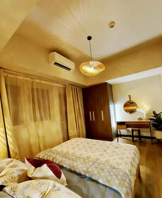 a hotel room with two beds and a table at Condo- Park McKinleyWest Big1Br unit -Pool View in Manila