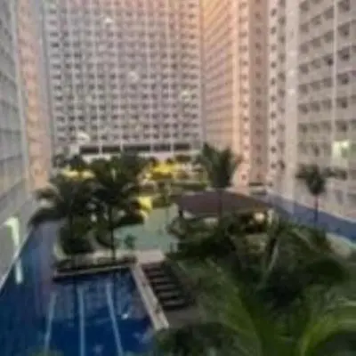a view of a building with a pool and palm trees at SHORE Residence d42 walking distance MOA near Airport in Manila