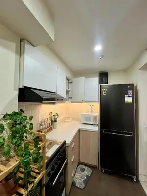 a kitchen with a black refrigerator and white cabinets at SRR NAIA T3 - Month of January - New Year PROMO Php 1,999 - 1 BR Interior Designed Unit in Manila
