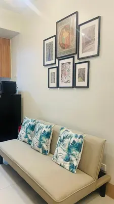 a couch in a living room with pictures on the wall at Luna Suite in Manila