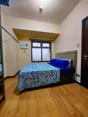 a bedroom with a bed with blue sheets and a window at Levi & Moon's Chill with beautiful view in Manila