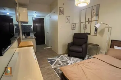 a bedroom with a bed and a chair and a kitchen at Pause Point - Standford 3 Suites in Silang