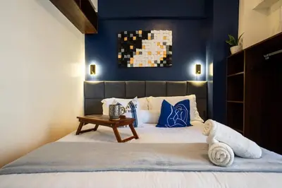 a bedroom with a bed with a blue wall at Prime 2-BR apartment near major business districts in Manila