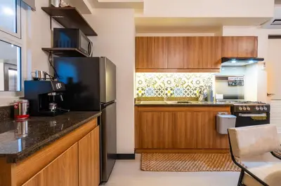 a kitchen with wooden cabinets and a black refrigerator at Prime 2-BR apartment near major business districts in Manila
