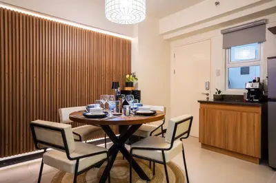 a dining room with a table and four chairs at Prime 2-BR apartment near major business districts in Manila