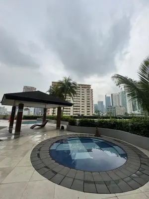 a swimming pool with a table and a umbrella at The Beacon Makati in Manila