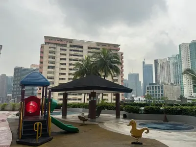a playground with a slide and an umbrella in a city at The Beacon Makati in Manila