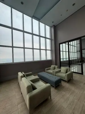 a large room with couches and chairs and windows at The Beacon Makati in Manila