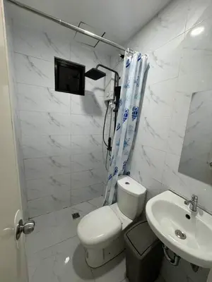 a white bathroom with a toilet and a sink at W Tramo Residences in Manila