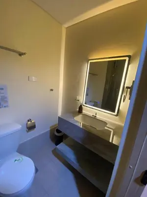 a bathroom with a sink and a toilet and a mirror at Hallin Bay Suites Modern 1BR with balcony in Manila
